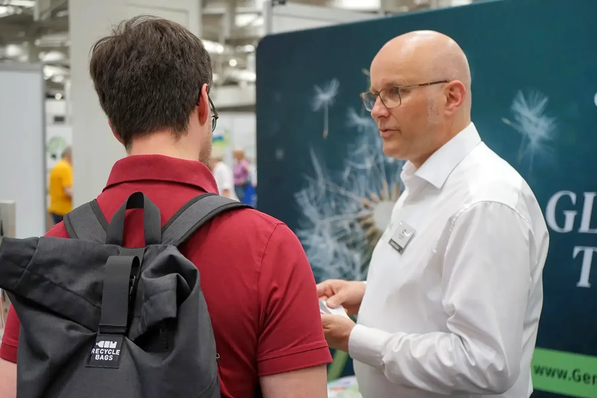 Gemeindebrief-Experte Detlef Brückner im Gespräch mit einem Interessenten am Messestand von GemeindebriefDruckerei.