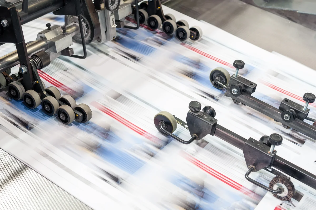 Bedruckte Papierbahn läuft durch eine Druckmaschine.
