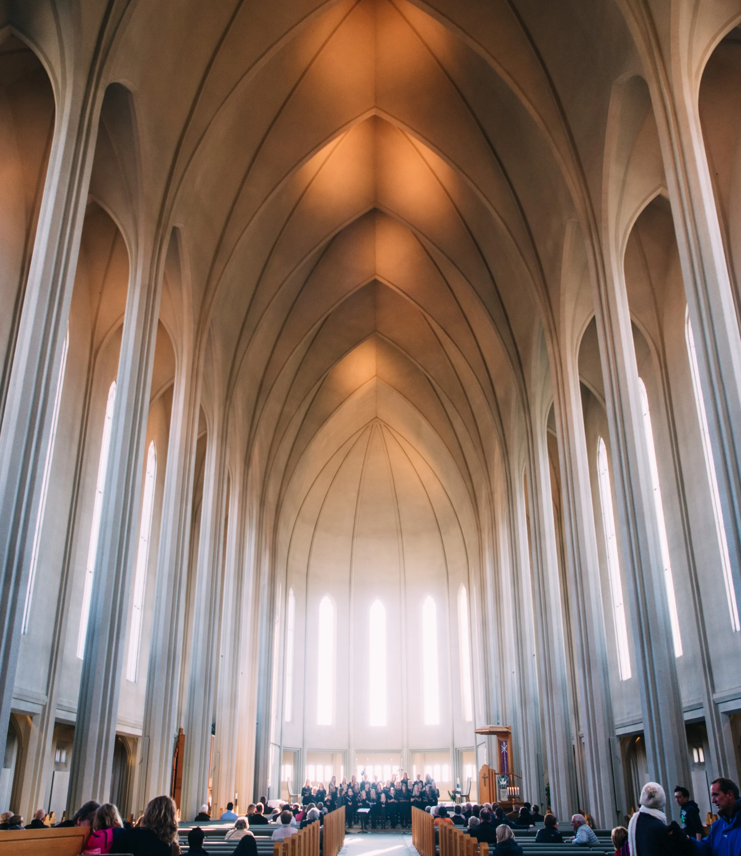 Chor singt im hellen Kirchenschiff einer hohen Kirche.