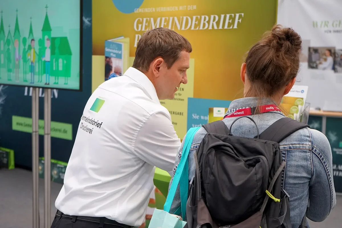 Mitarbeiter im Gespräch mit einem Messebesucher.